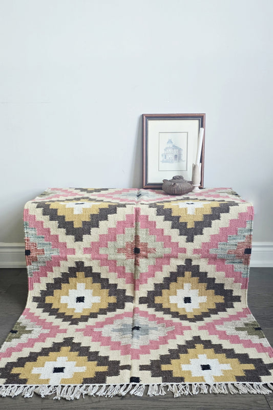 Patterned rug on a wooden floor with a framed picture in the background
